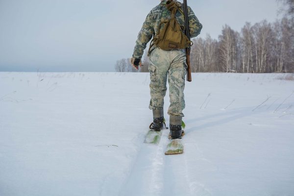 Hunter in winter walking with snow shoes or skis