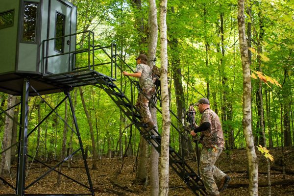 Two hunters climbing up stairs of elevated ambush blind