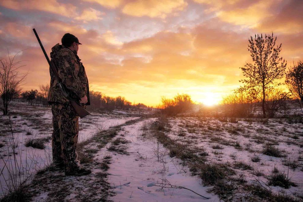 hunter looking at sunrise or sunset at Close of hunting season